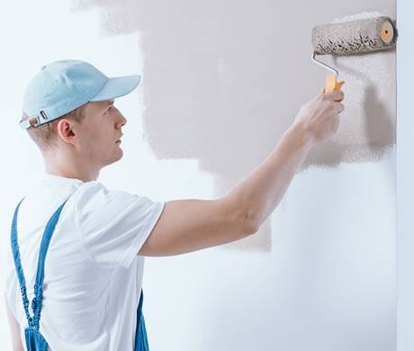 A professional painter applying fresh paint to the walls of a room, showcasing expert painting services for residential and commercial spaces.